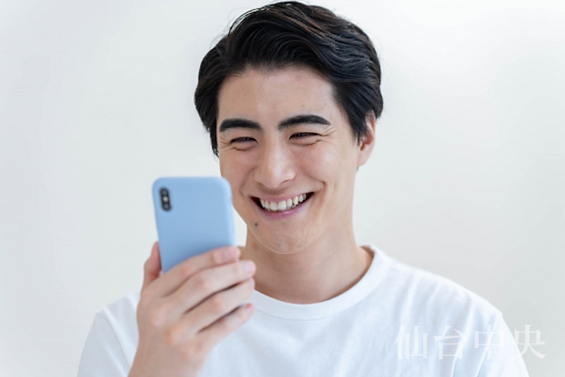 スマホから包茎手術の予約をする男性
